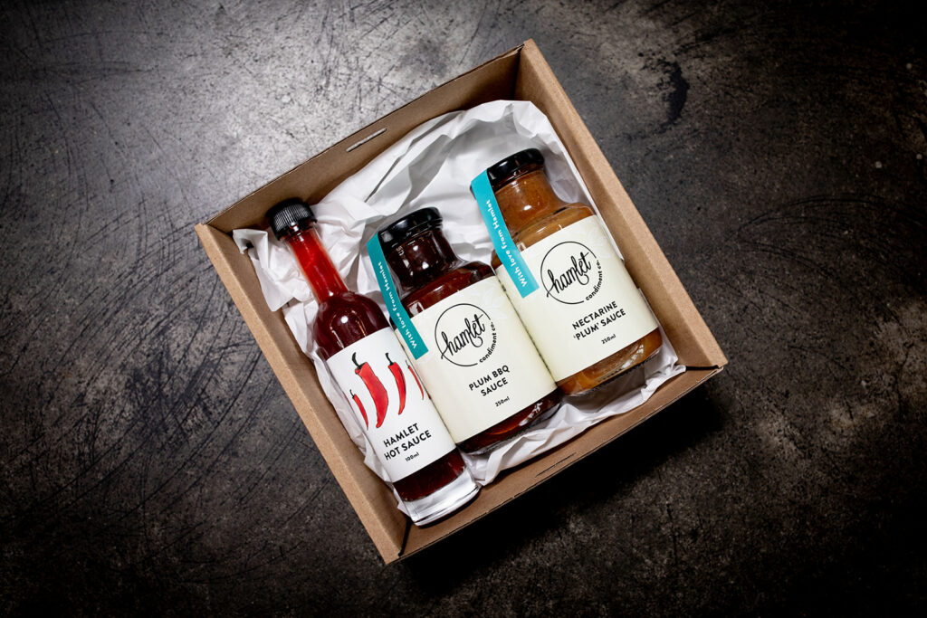 A hamper containing bottles of Hamlet's Hot Sauce, Plum BBQ Sauce and Nectarine Plum Sauce.