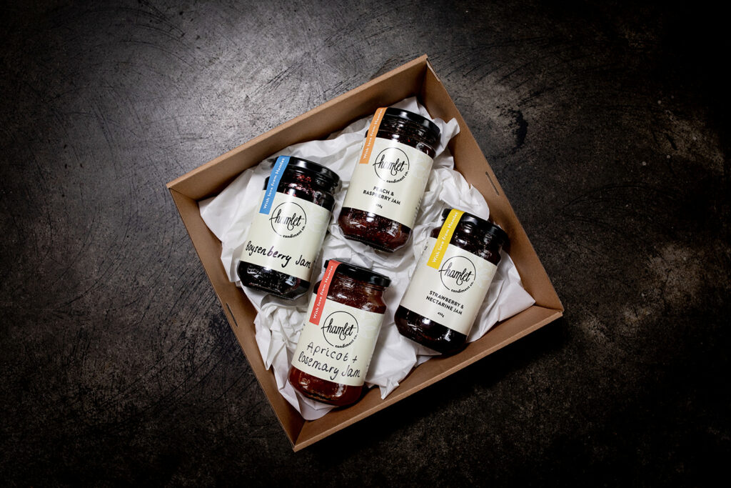 A hamper containing a jar of Hamlet's Boysenberry Jam, Peach and Raspberry Jam, Apricot and Rosemary Jam, and Strawberry and Nectarine Jam.