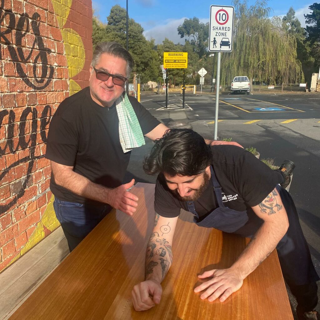 Italian-Australian chef Guy Grossi smiling for a photo standing next to one of Hamlet's participants giving him a pat on the back.