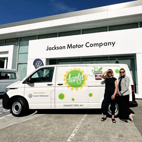 Hamlet's co-founder and CEO Emily standing with a representative of Jackson Motor Company in front of the new Hamlet Van featuring artwork by Paul McNeil.