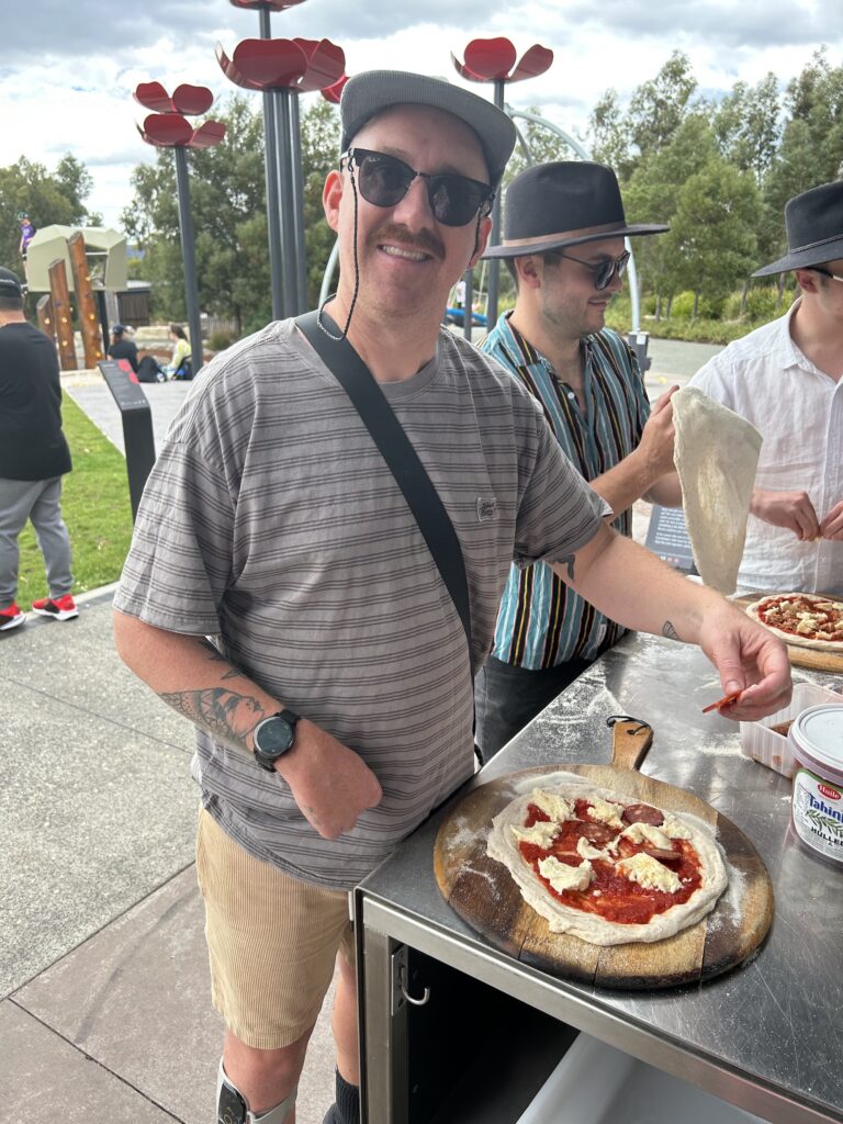 A Hamlet participant making a pizza in the park at the annual Hamlet celebration.