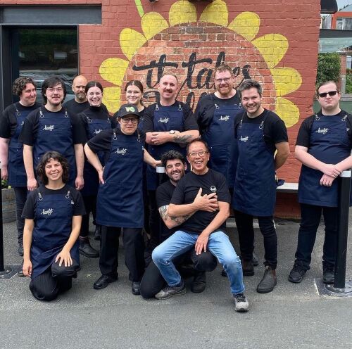 Group of Hamlet team members standing together and smiling for a photo wearing black t-shirts and navy Hamlet aprons.