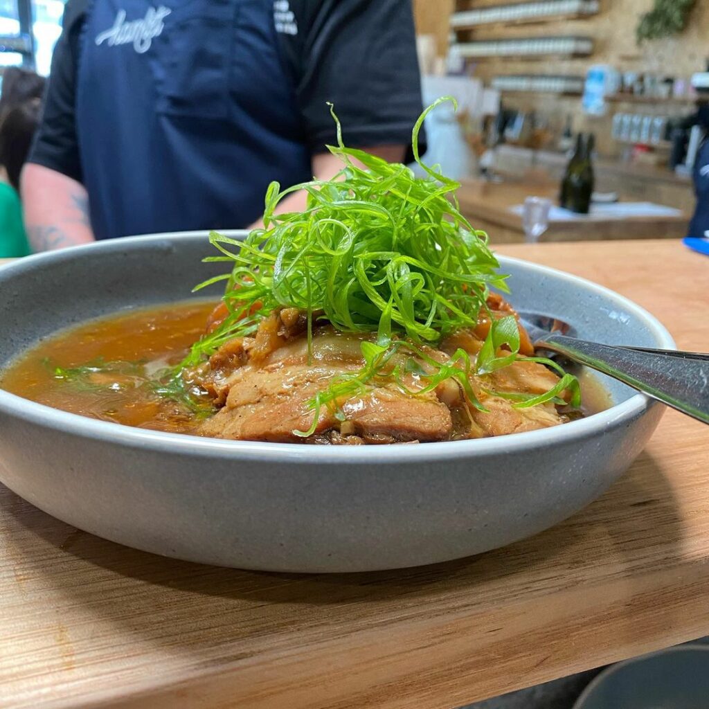 Large bowl of Hamlet's asian soup with green salad garnish on top.