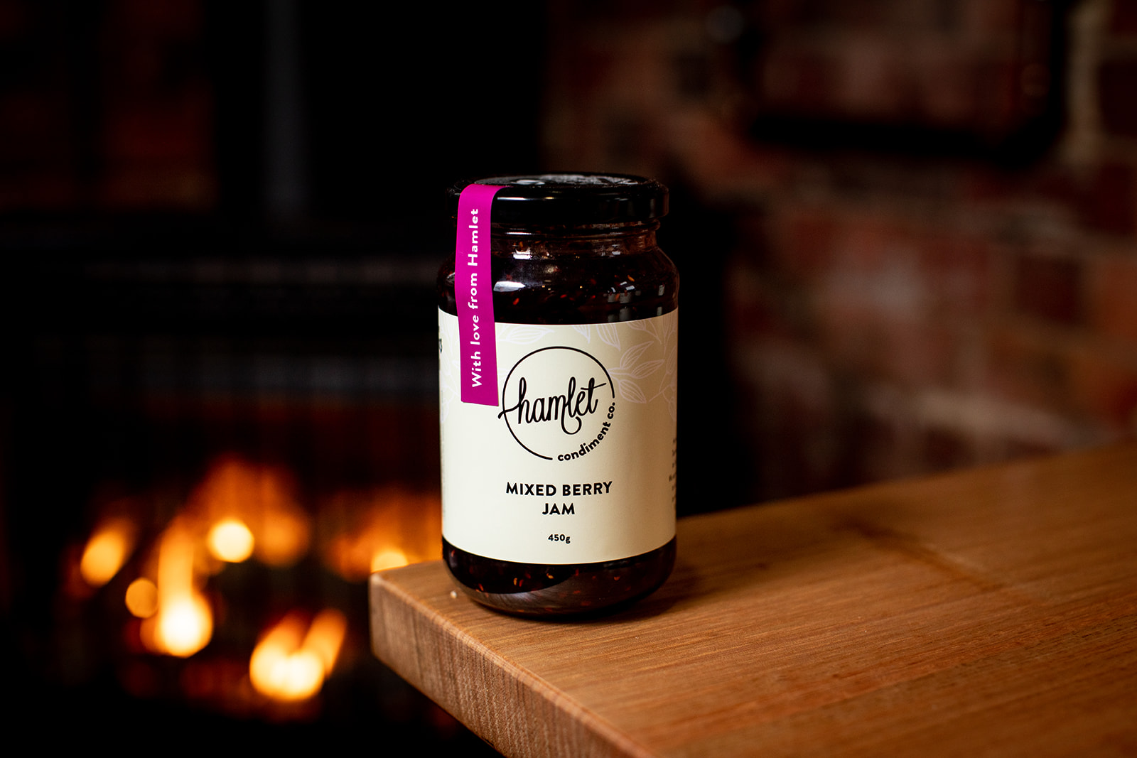 A jar of Hamlet's Mixed Berry Jam sitting on a timber table.
