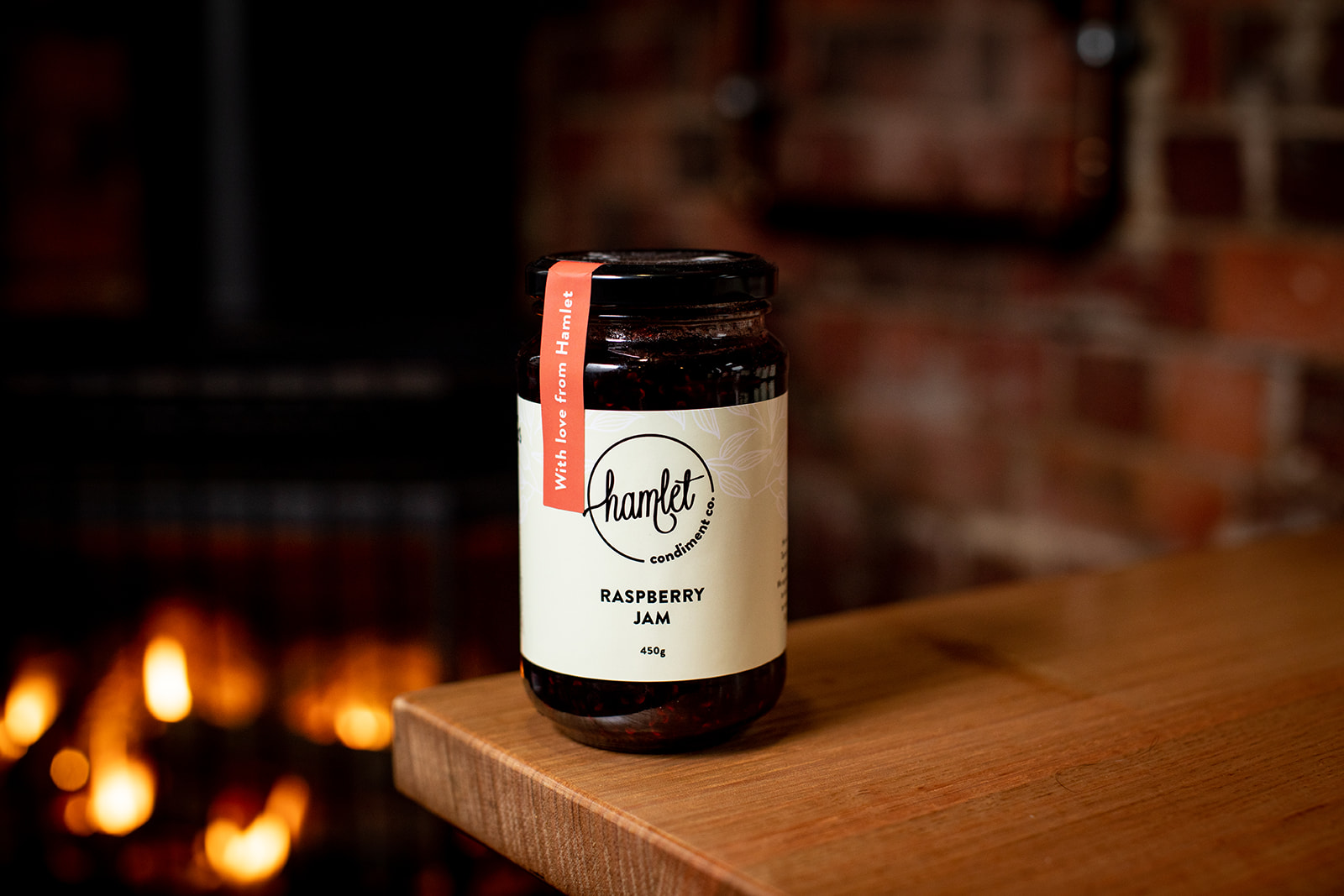 A jar of Hamlet's Raspberry Jam sitting on a timber table.