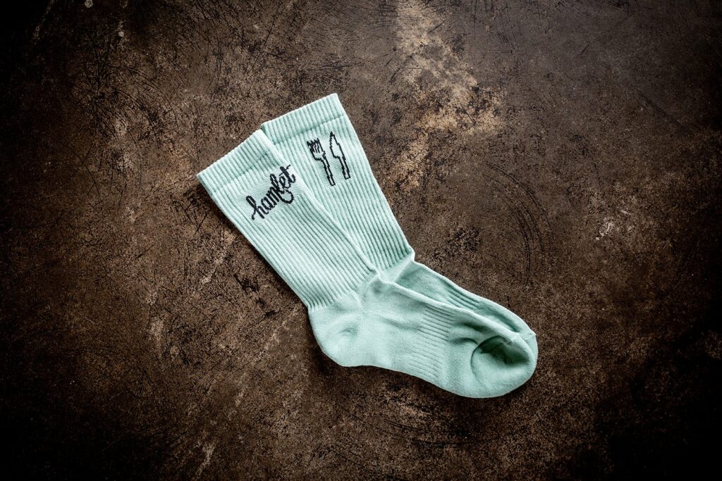 A pair of Hamlet's socks sitting on a concrete bench with artwork by their work experience participants.