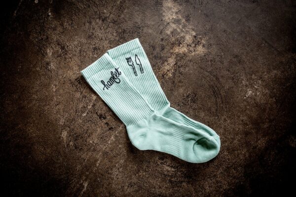 A pair of Hamlet's socks sitting on a concrete bench with artwork by their work experience participants.