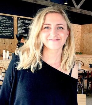 Hamlet's co-founder and CEO Emily smiling for a photo in the cafe wearing a black t-shirt.
